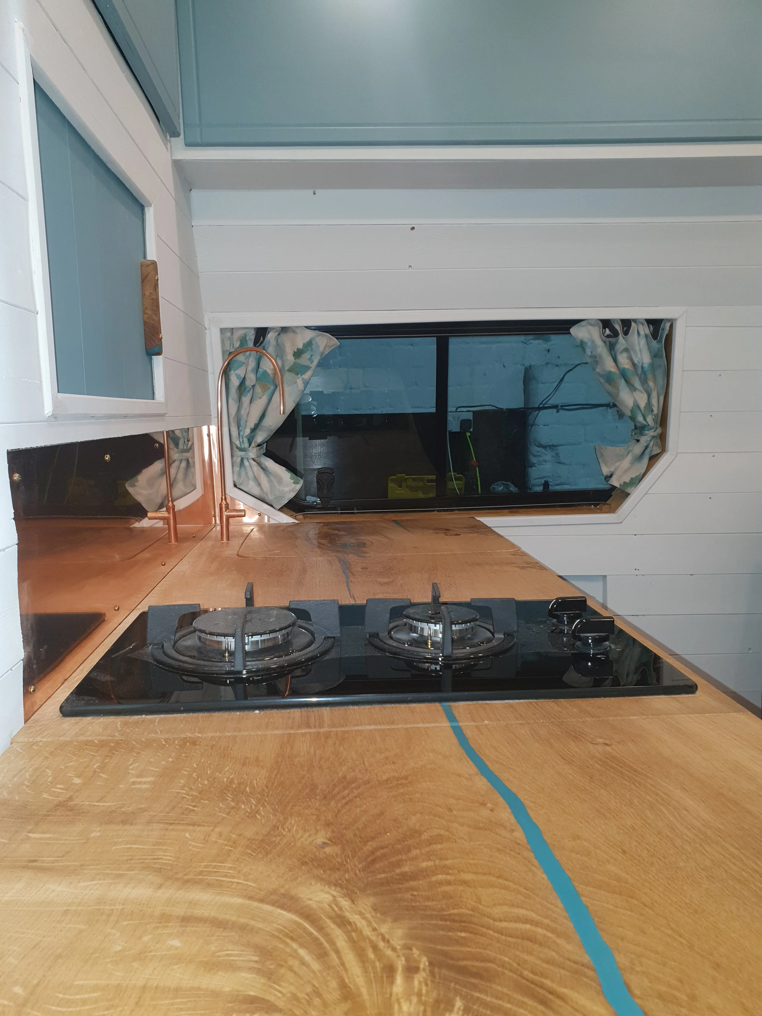 High-roof Vauxhall Vivaro. Semi-fixed bed, Garage space, Heated drying room, Pull out rails, Copper tap, Epoxy poured oak worksurface, Butlers sink, 2 ring hob.