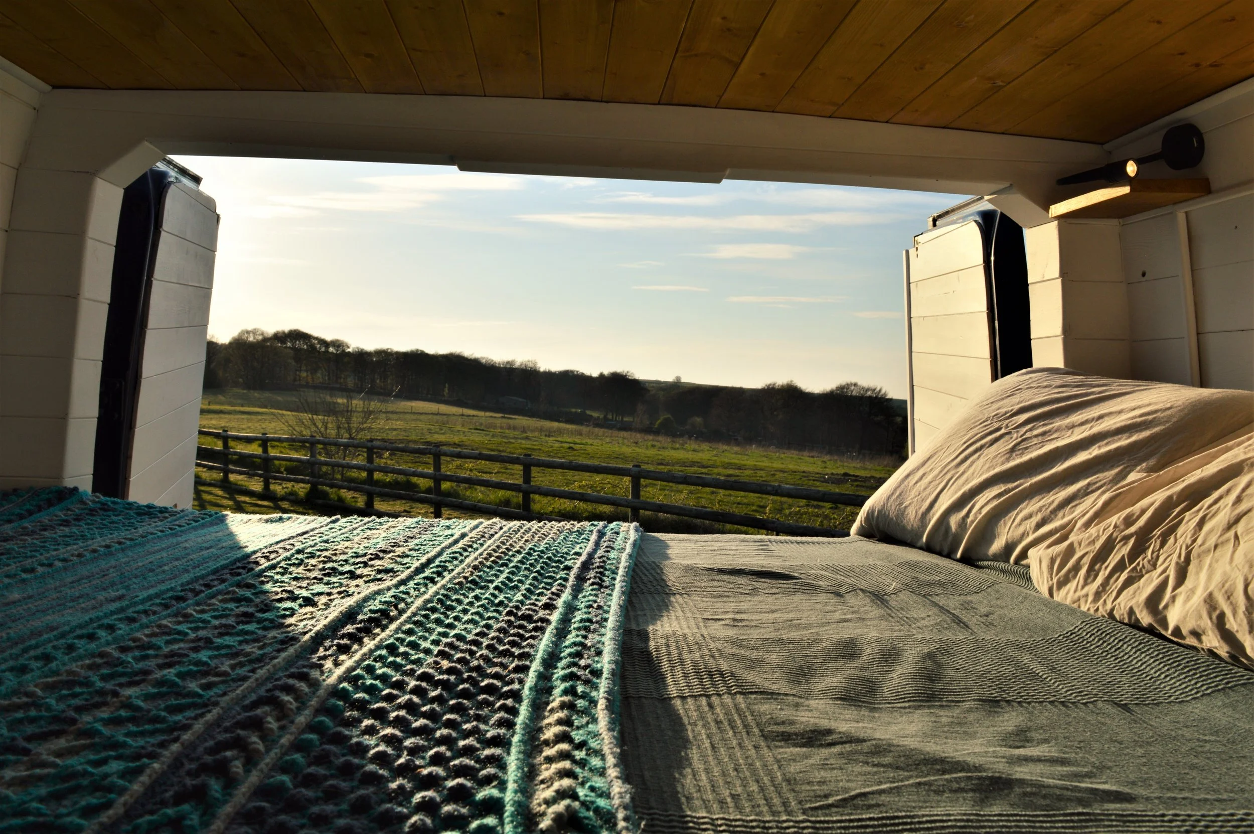 A finished conversion, looking out from the bed across a green field.