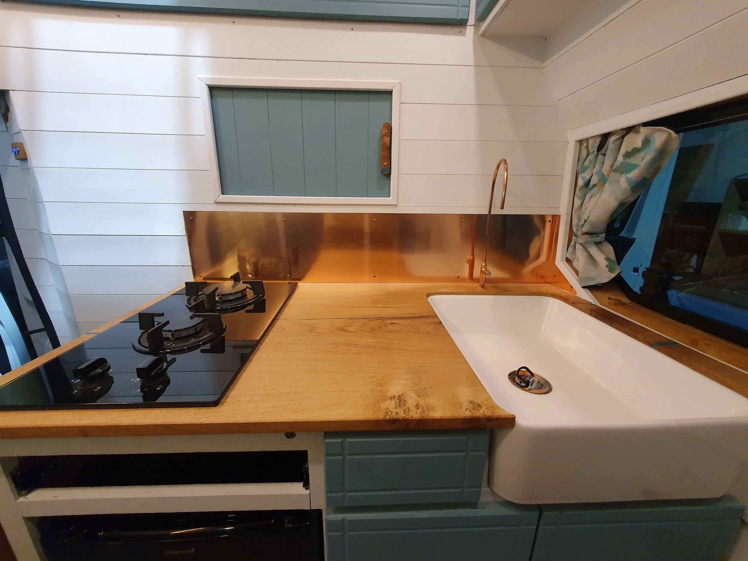 High-roof Vauxhall Vivaro. Semi-fixed bed, Garage space, Heated drying room, Pull out rails, Copper tap, Epoxy poured oak worksurface, Butlers sink, 2 ring hob. Photo 8 of 9.