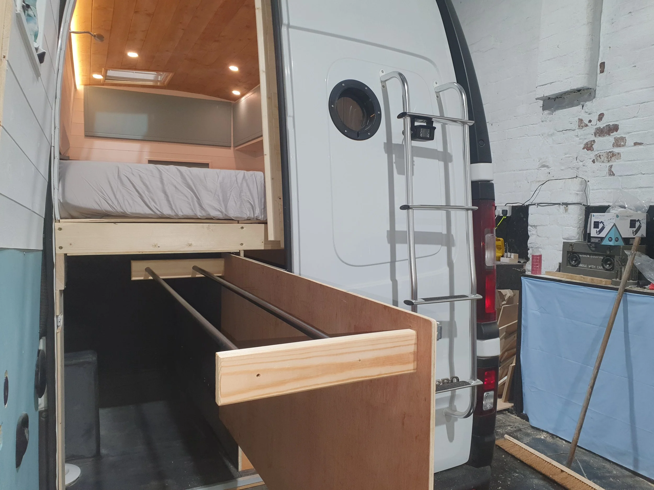 High-roof Vauxhall Vivaro. Semi-fixed bed, Garage space, Heated drying room, Pull out rails, Copper tap, Epoxy poured oak worksurface, Butlers sink, 2 ring hob. Photo 4 of 9.